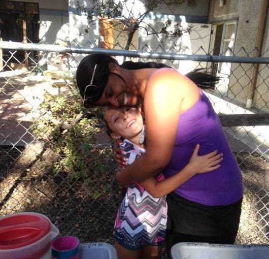 Caregiver hugging a child beside the garden beds