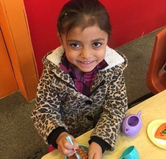 Toddler smiling over a pretend tea party