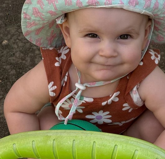 Smiling baby in a sun hat holding a ball