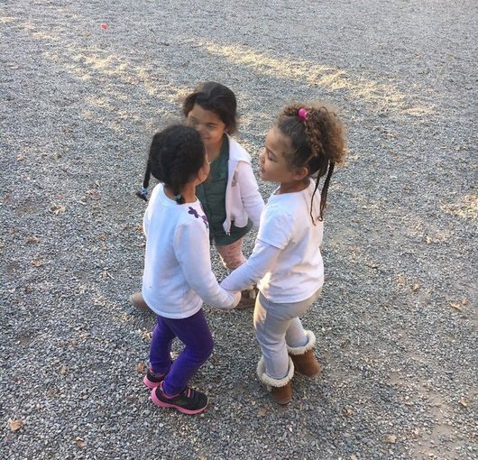 Two young friends holding hands in the play yard