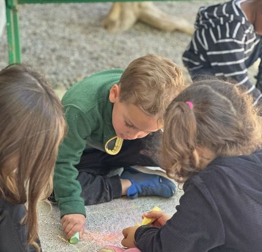 Children drawing together on the classroom floor