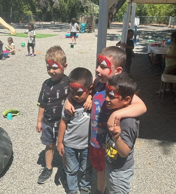 Three boys with face paint hugging outdoors at Super Kidz Club