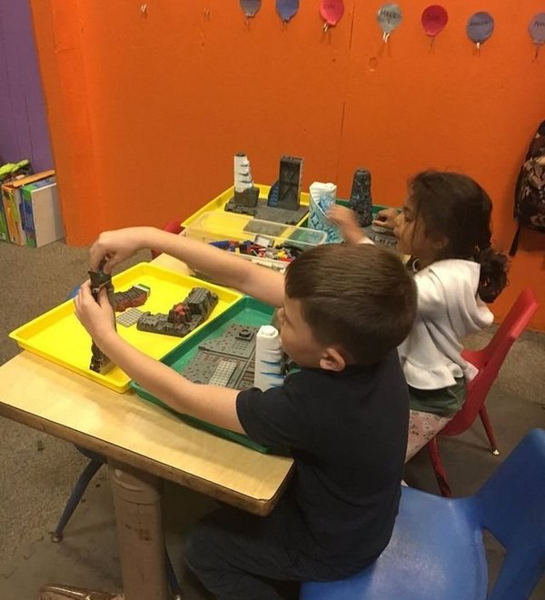 Children playing together at a classroom table at Super Kidz Club