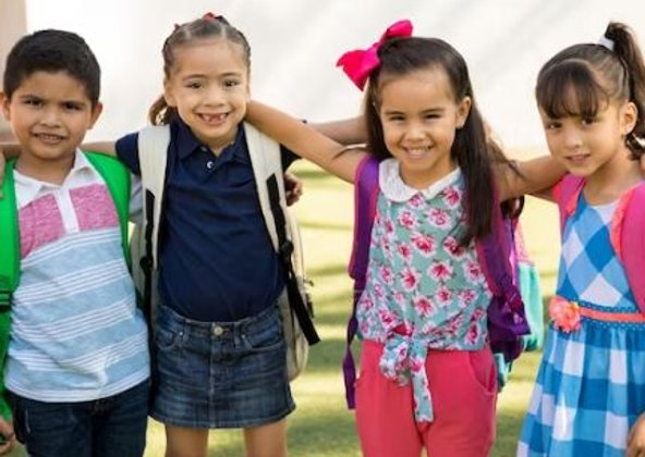 Two smiling girls with backpacks after school