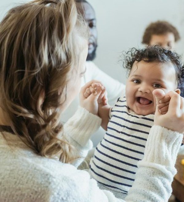 Caregiver holding a smiling baby in the Super Kidz Club infant room