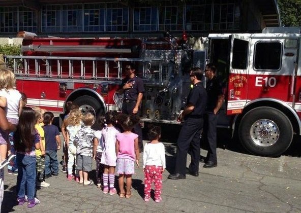 Children gather beside a Contra Costa County fire engine while firefighters talk with the group