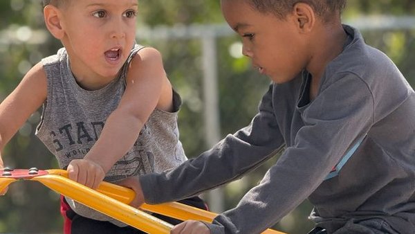 Two children climbing on a play structure in the Super Kidz Club yard