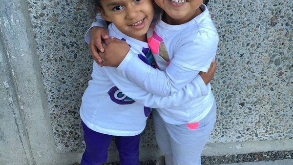Two young siblings hugging outside Super Kidz Club
